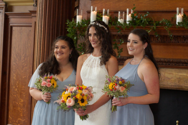Bride and two bridesmaids holding bouquets of wildflowers