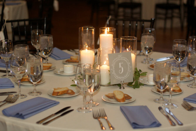 Glass encased pillar candle centerpiece with touches of accenting greenery