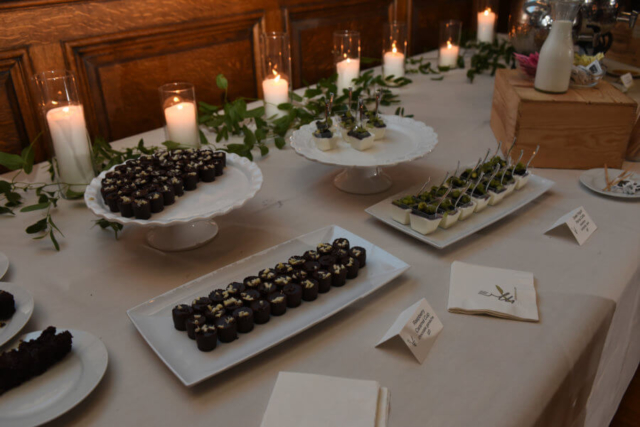 Dessert table with accenting candles and greenery.